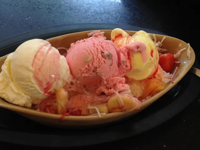 Three scoops of ice cream with fruit and syrup in a boat-shaped bowl