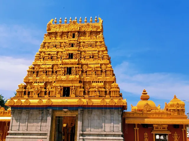 The gold gopuram of the Kudroli Gokarnanatha Temple against a blue sky