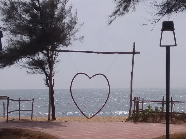 A heart-shaped swing frame on the paved path down to Padubidri's beach