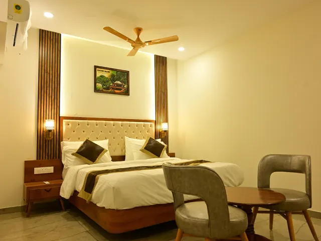 A deluxe room with a double bed, a panelled headboard and a small table