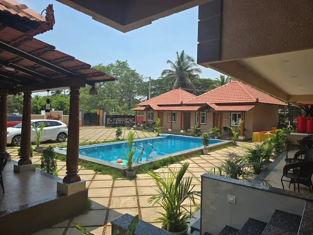 The pool and tiled-roof cottages seen from under a pergola by day